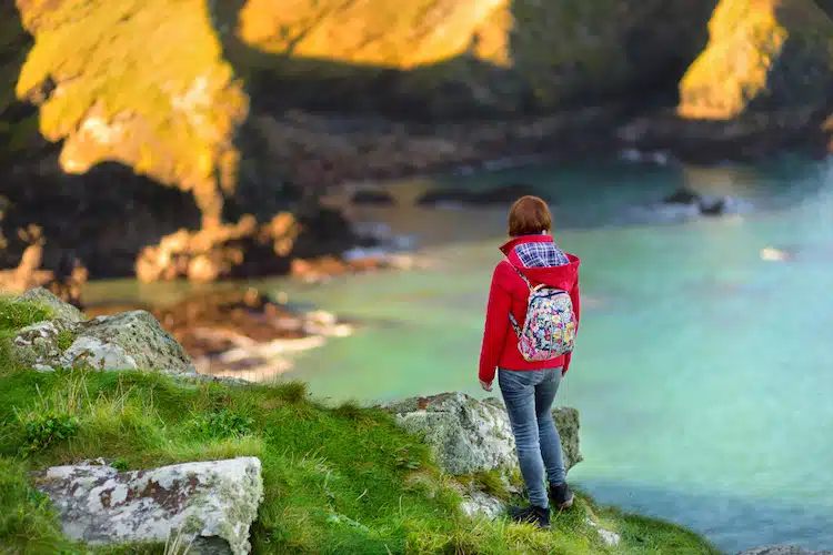 Tourist enjoying view of scenic rugged Cornish coastline