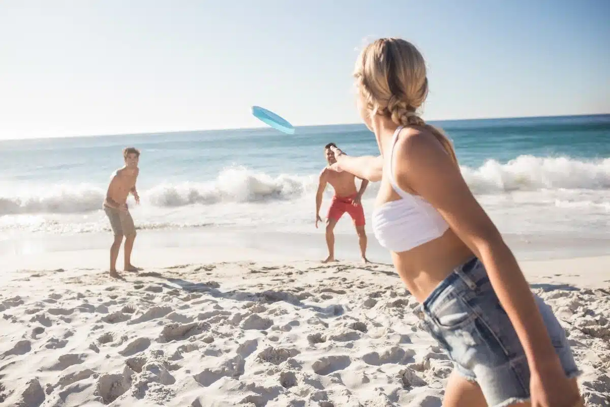 Friends playing with a frisbee on the beach