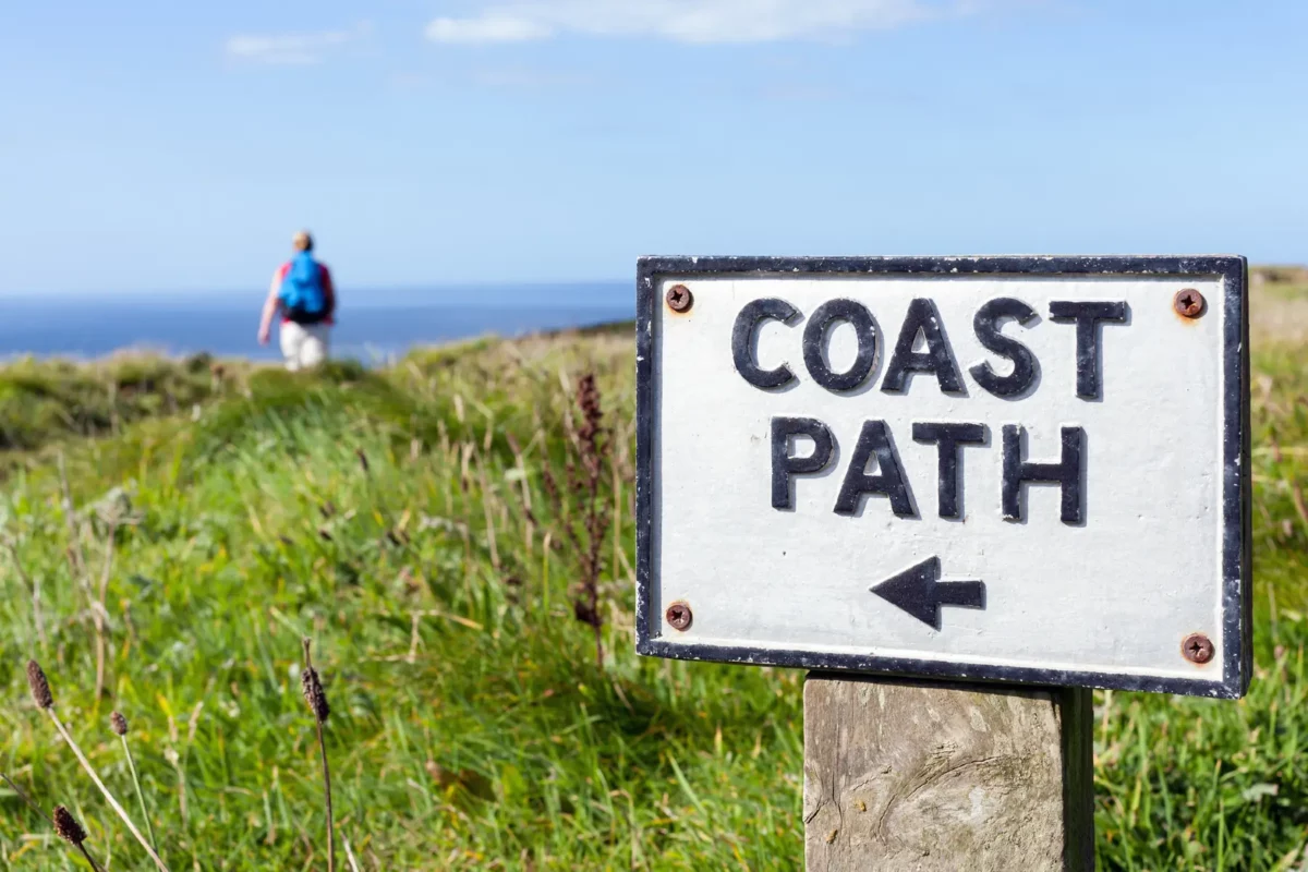Walker and sign on the coast path
